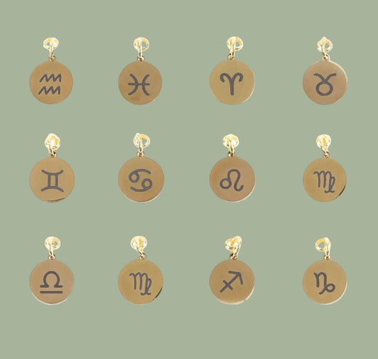 Set of gold and bronze zodiac charm pendants on a white background