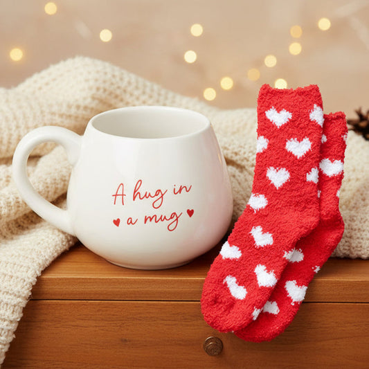 A Hug in a Mug gift set featuring a round white ceramic mug with red heart script and cosy red fluffy socks with white heart print