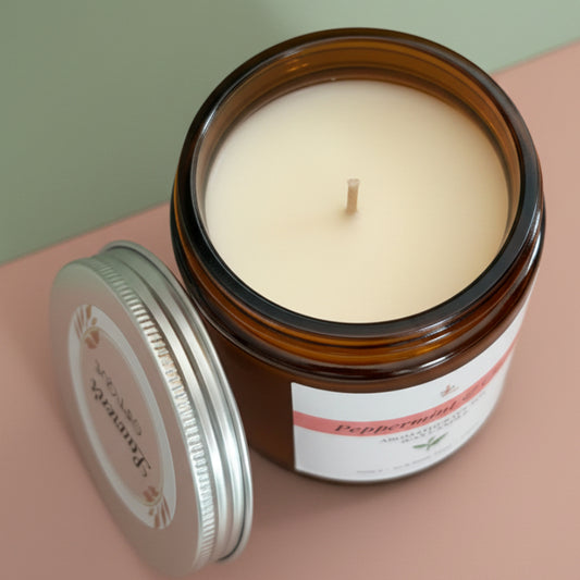 Candle in a glass jar with a visible label on a pink background