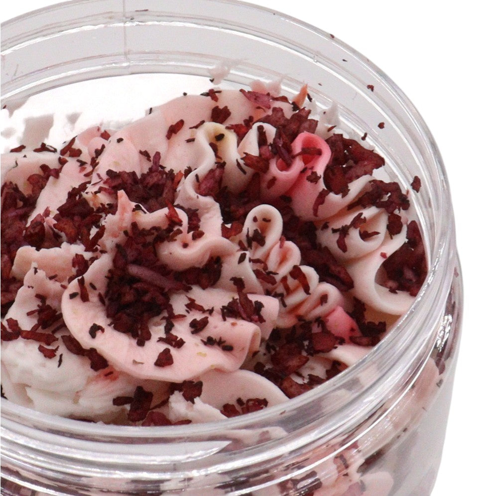 Jar of pink and white whipped soap with  shavings on a white background