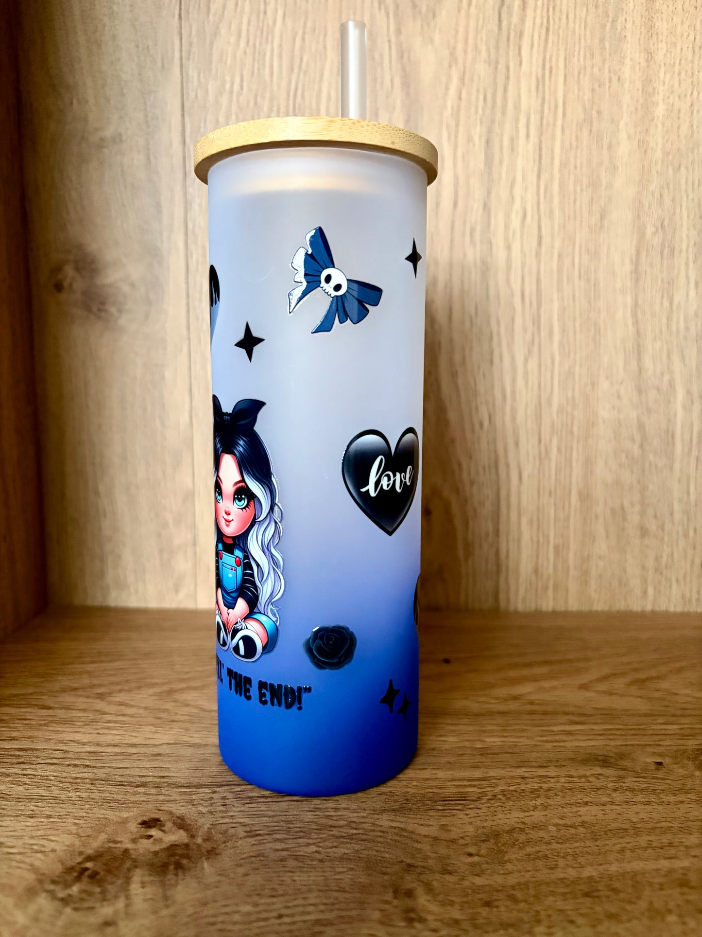 Blue frosted glass with black heart and rose designs on a wooden background 