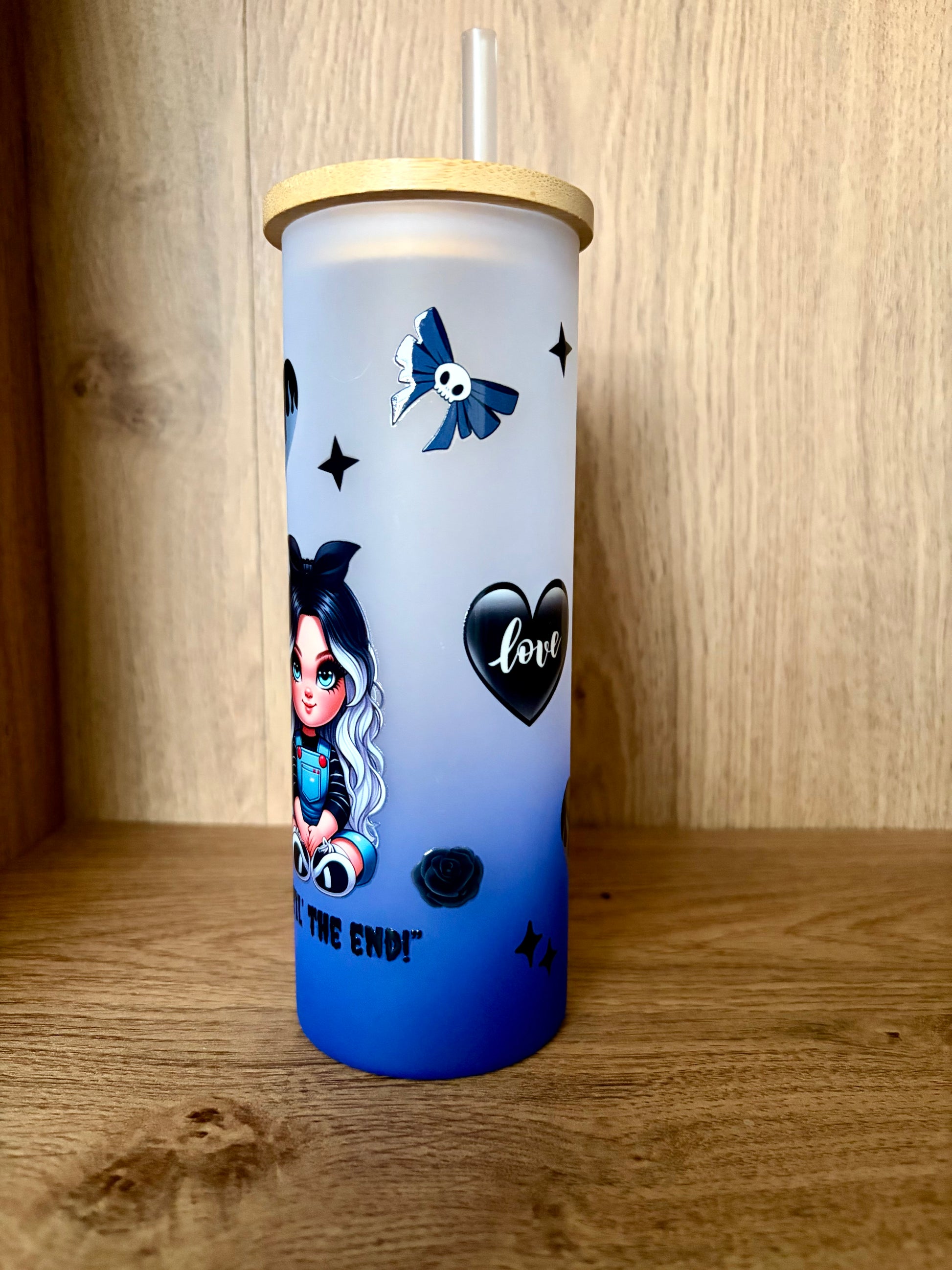 Blue frosted glass with black heart and rose designs on a wooden background 