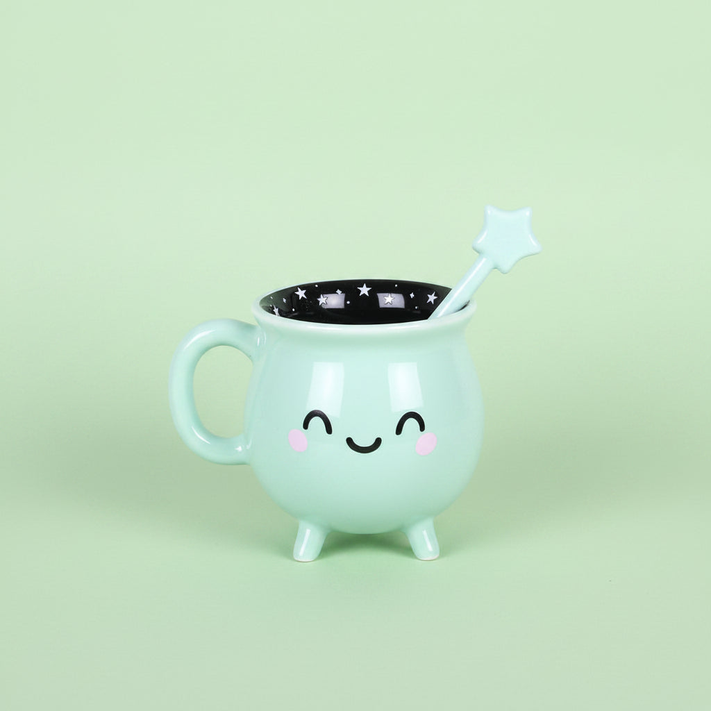 Mint green mug with a face, star-shaped handle, and black interior on a green background