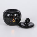 black pumpkin shaped oil burner with lid on a grey background