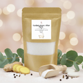 Kraft paper packaging of Eucalyptus, Ginger, and Black Pepper aromatherapy bath salts with a wooden scoop on a white background.