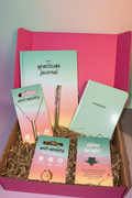Gift set with gratitude journal, notebook, and anti-anxiety necklaces on a pink background