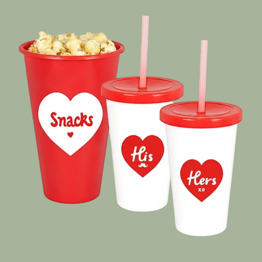 Red and white cups with heart designs and straws, one containing popcorn.