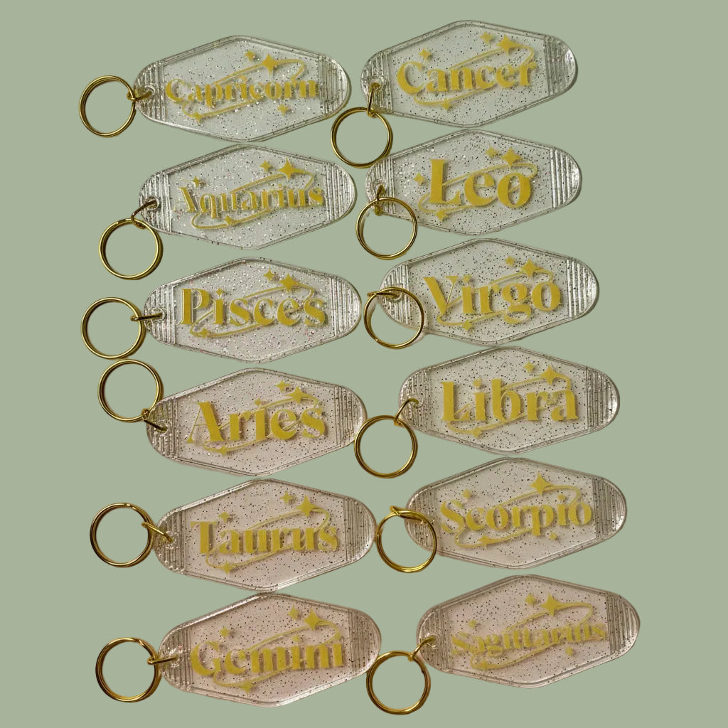 Set of zodiac keychains with gold text on a white background