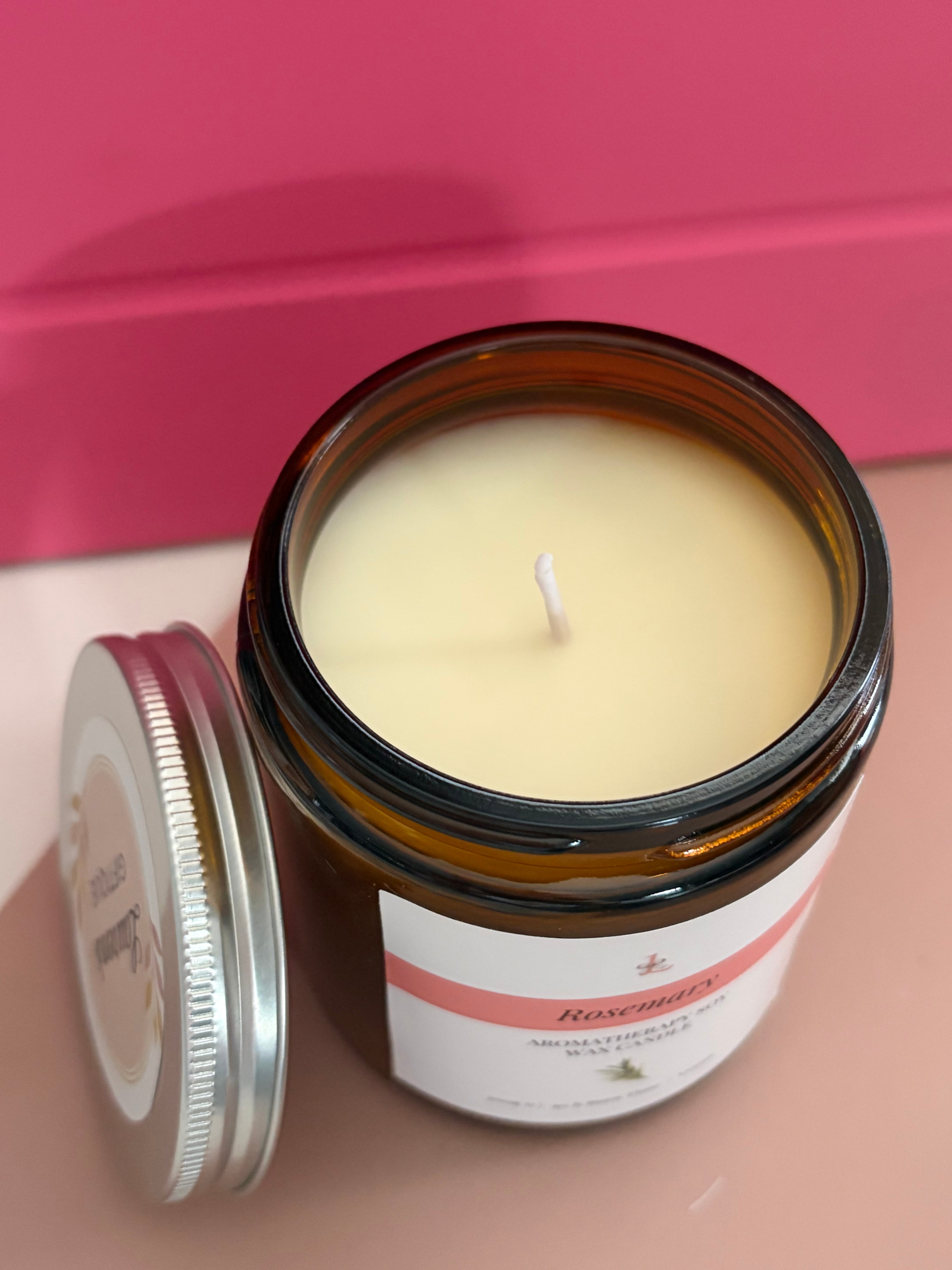Candle in a glass jar with a label on a pink background