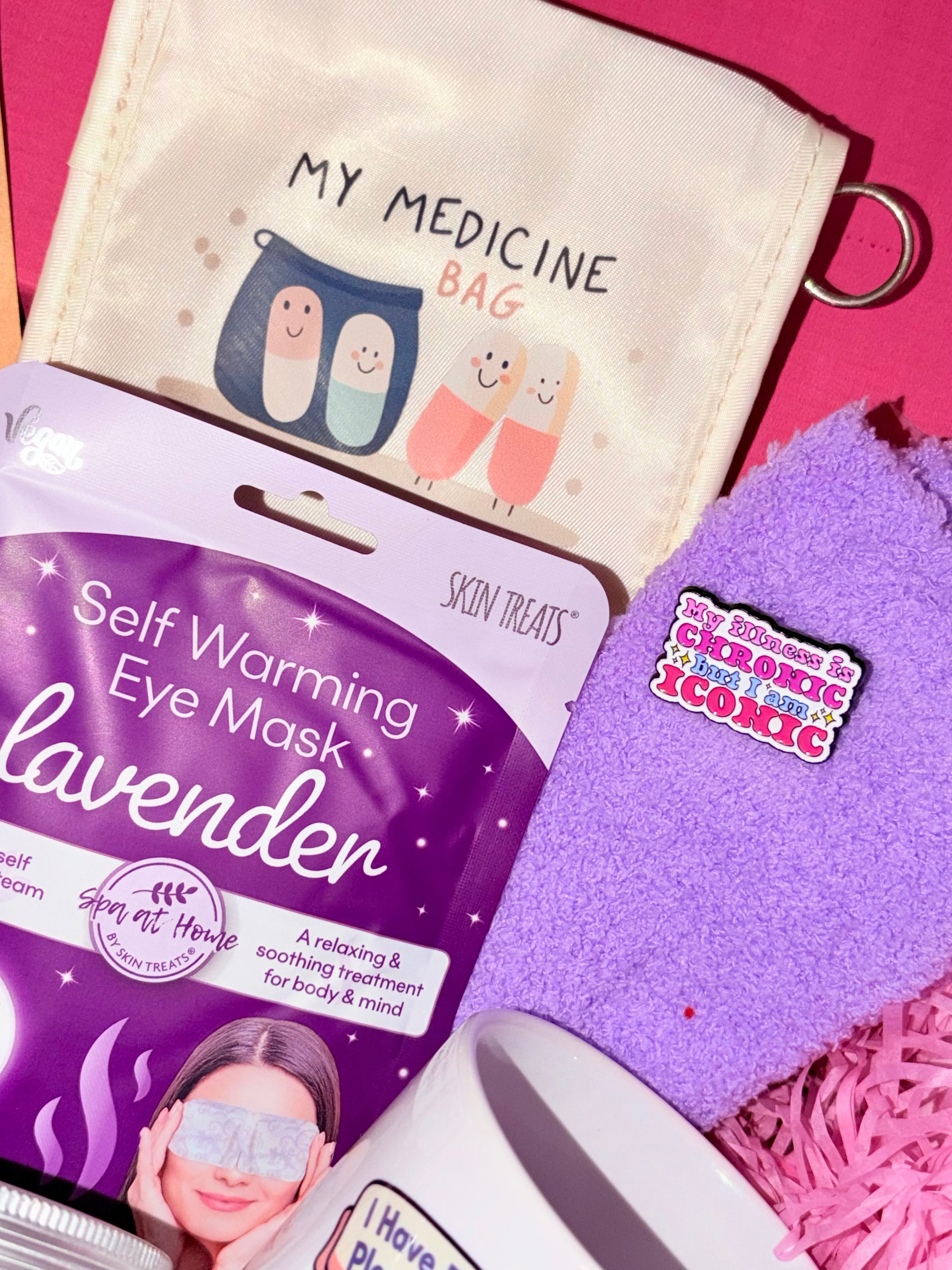 Self-warming eye mask with lavender scent, 'My Medicine Bag' pouch, and pink towel on a pink background.