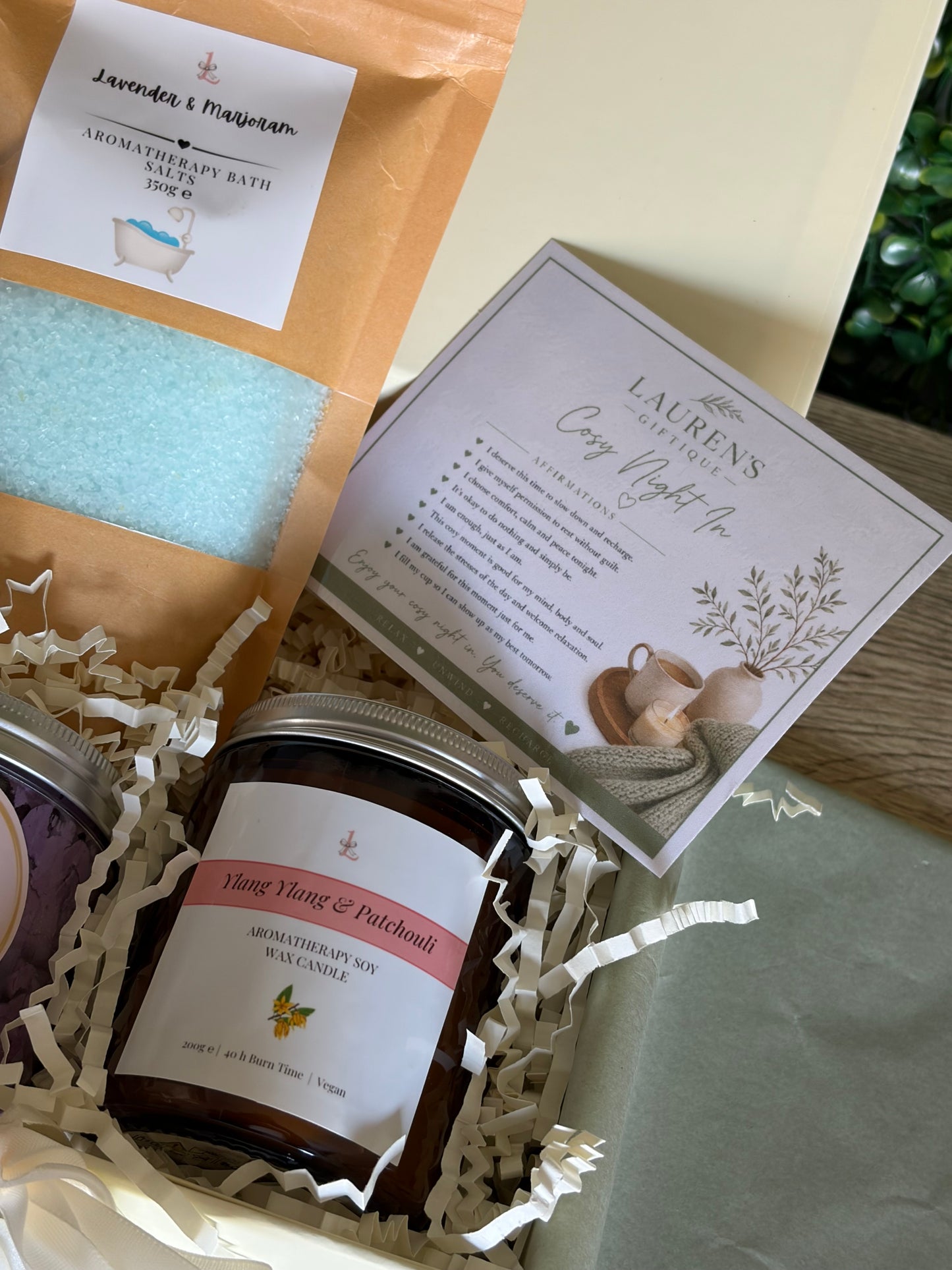 ylang ylang & patchouli aromatherapy candle, lavender & marjoram bath potion and cosy night in affirmations card on cream crinkle paper