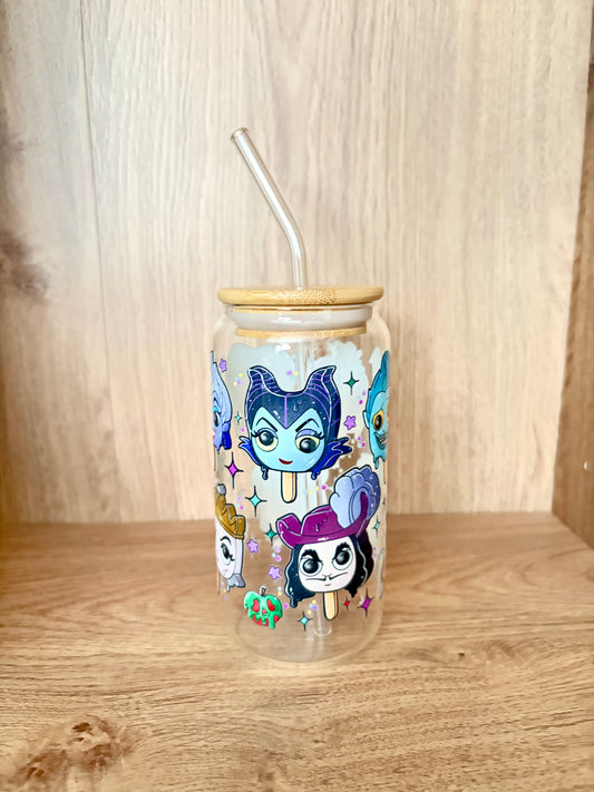 A clear glass tumbler with a bamboo lid and clear glass straw, decorated with colorful cartoon character illustrations, set on a wooden surface against a wooden background.