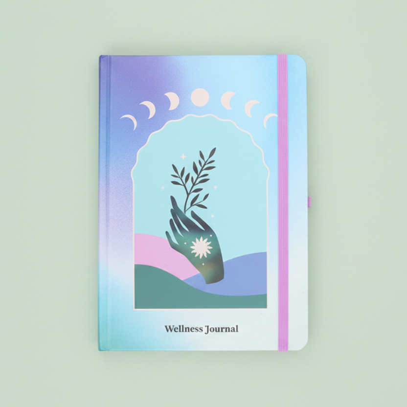 A pastel-colored wellness journal with a cover illustration of a hand holding a plant and moon phases, set against a plain sage green background.