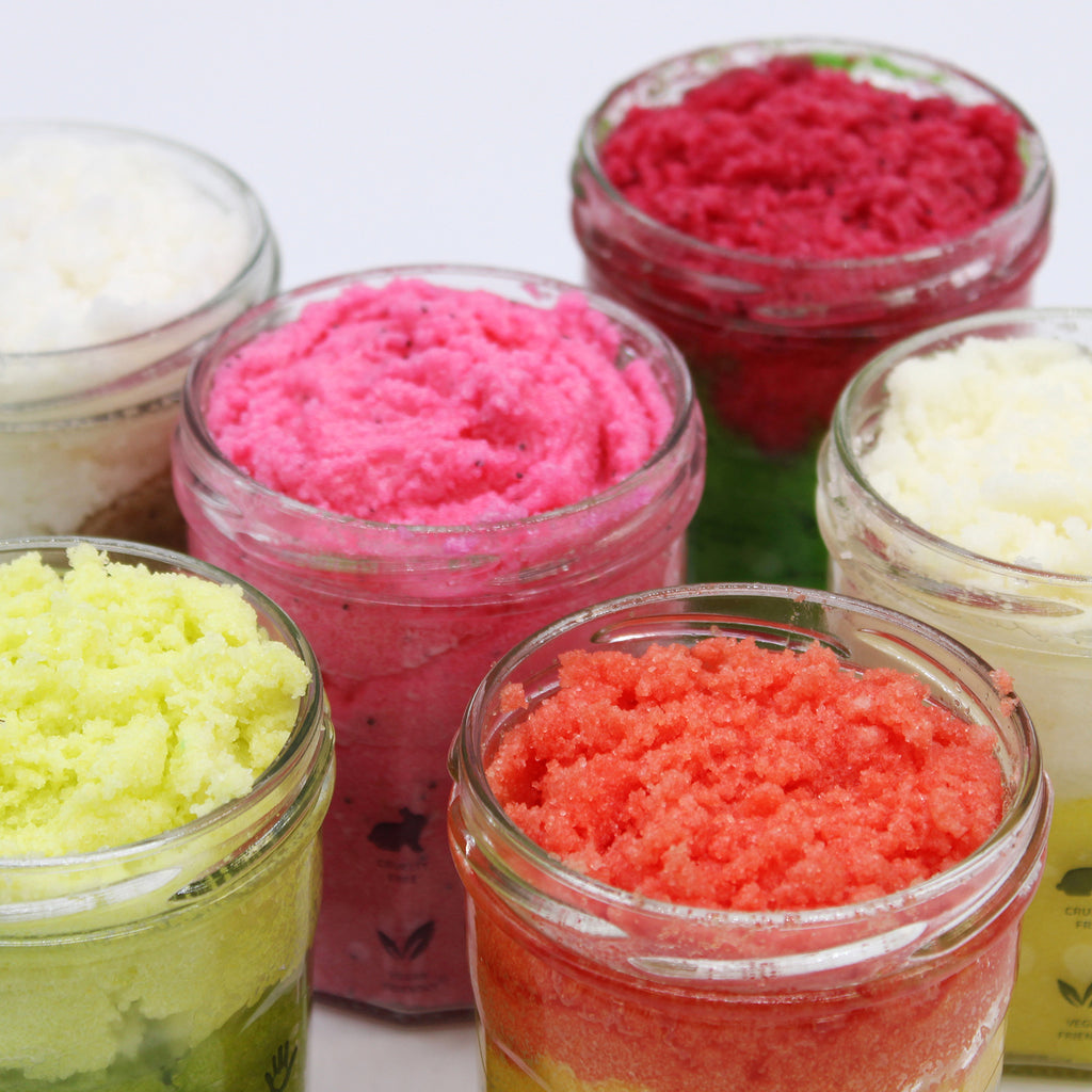 open jars of sugar body scrubs in a variety of colours