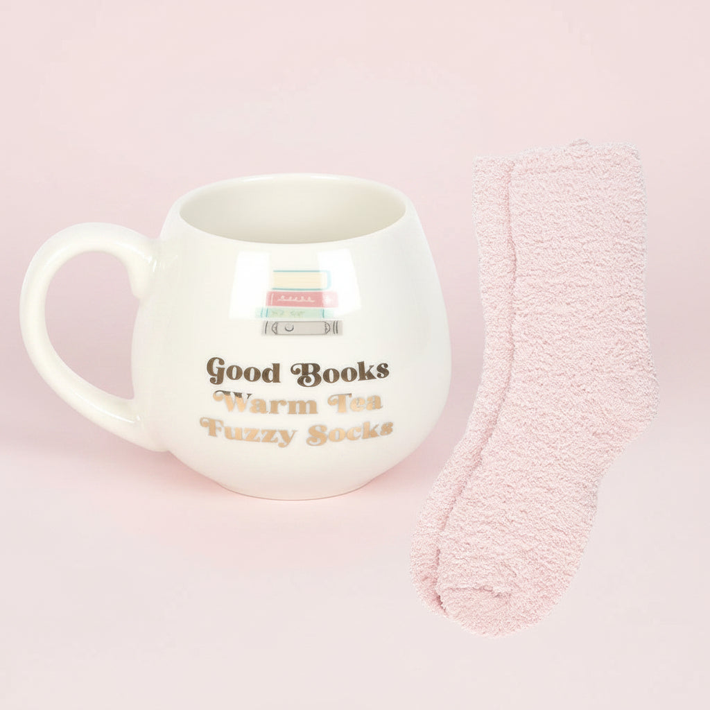 White mug with text and pink fuzzy socks on a pink background