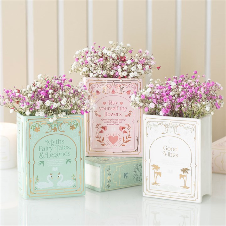 Decorative book planters with flowers on a light wooden surface.