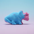 Blue and purple dinosaur-shaped bath bomb on a blue/purple background