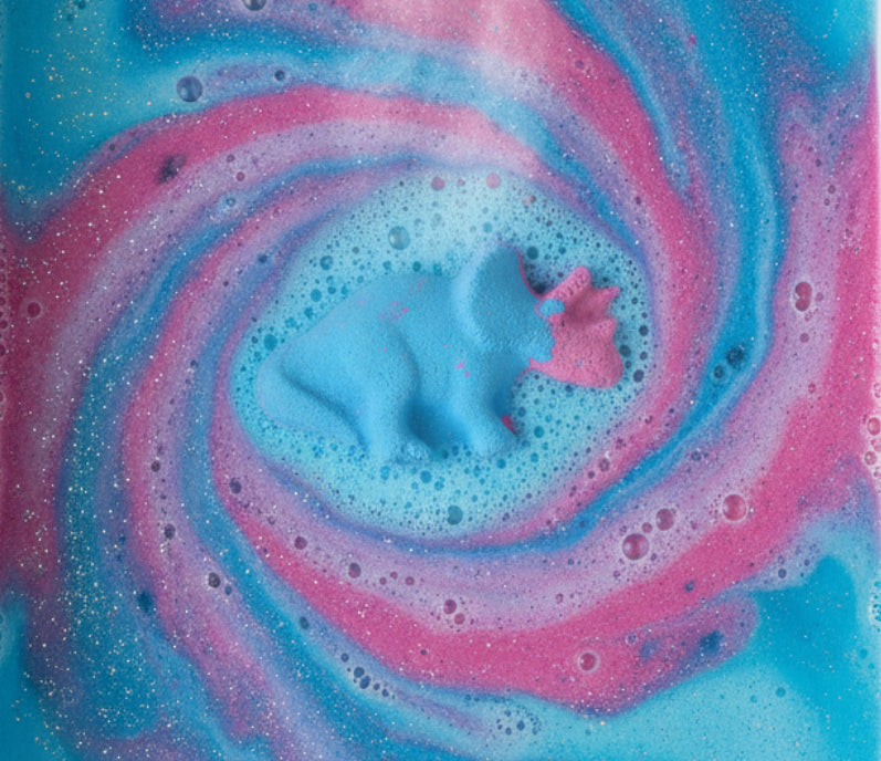 Blue and purple dinosaur-shaped bath bomb on a waterbackground
