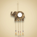 Decorative brass elephant with hanging bells on a light gold background