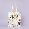 tote bag with witch, ghosts, cats and pumpkins on a purple background