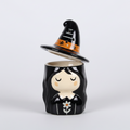 Decorative Halloween-themed figurine oil burner with a witch design on a grey background
