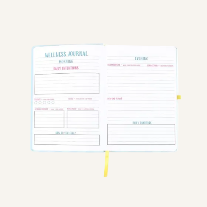 An open wellness journal with lined pages, featuring a light blue cover and yellow ribbon bookmarks, shown against a plain ivory background.