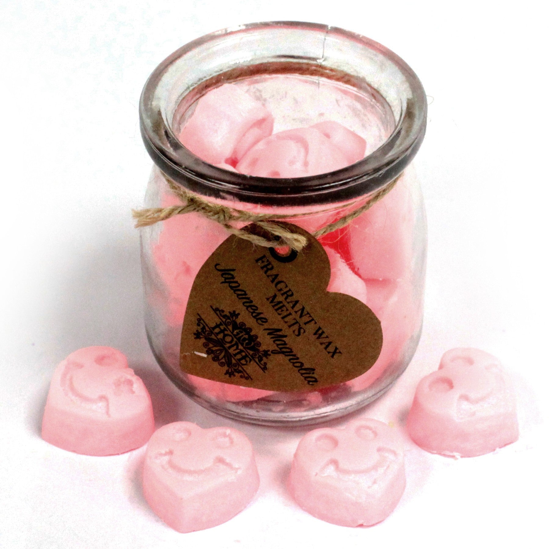Glass jar filled with pink wax melts on a white background