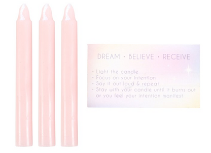Set of three pink candles with a motivational card on a white background