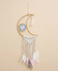 Decorative dreamcatcher with feathers hanging against a beige background