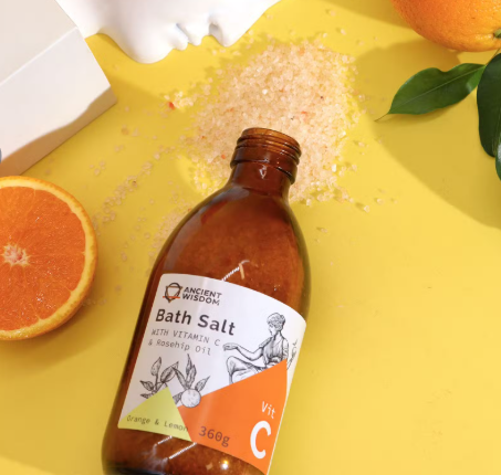 Bottle of bath salt with an orange on a yellow background