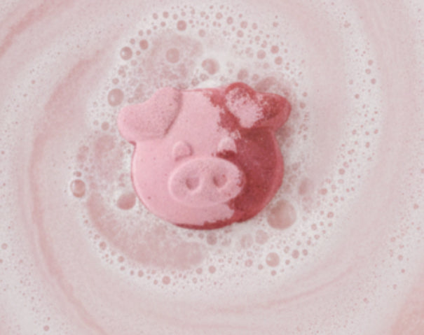 Pink pig-shaped bath bomb on a water fizzing background
