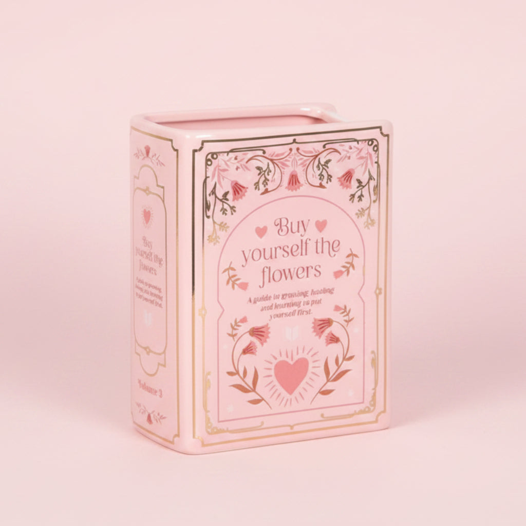 pink book vase with text 'buy yourself the flowers' on a pink background