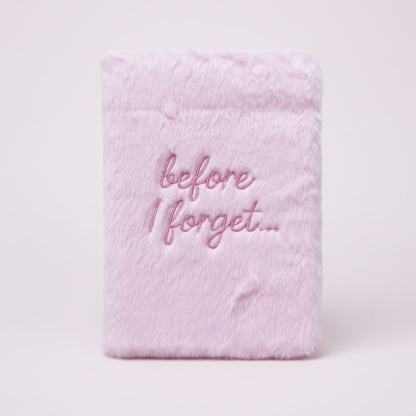 Pink fuzzy notebook with 'before I forget...' text on a pink background