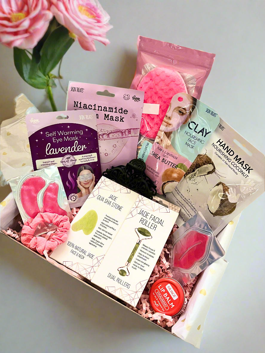 Box of self-care products including face masks and rollers on a light surface.