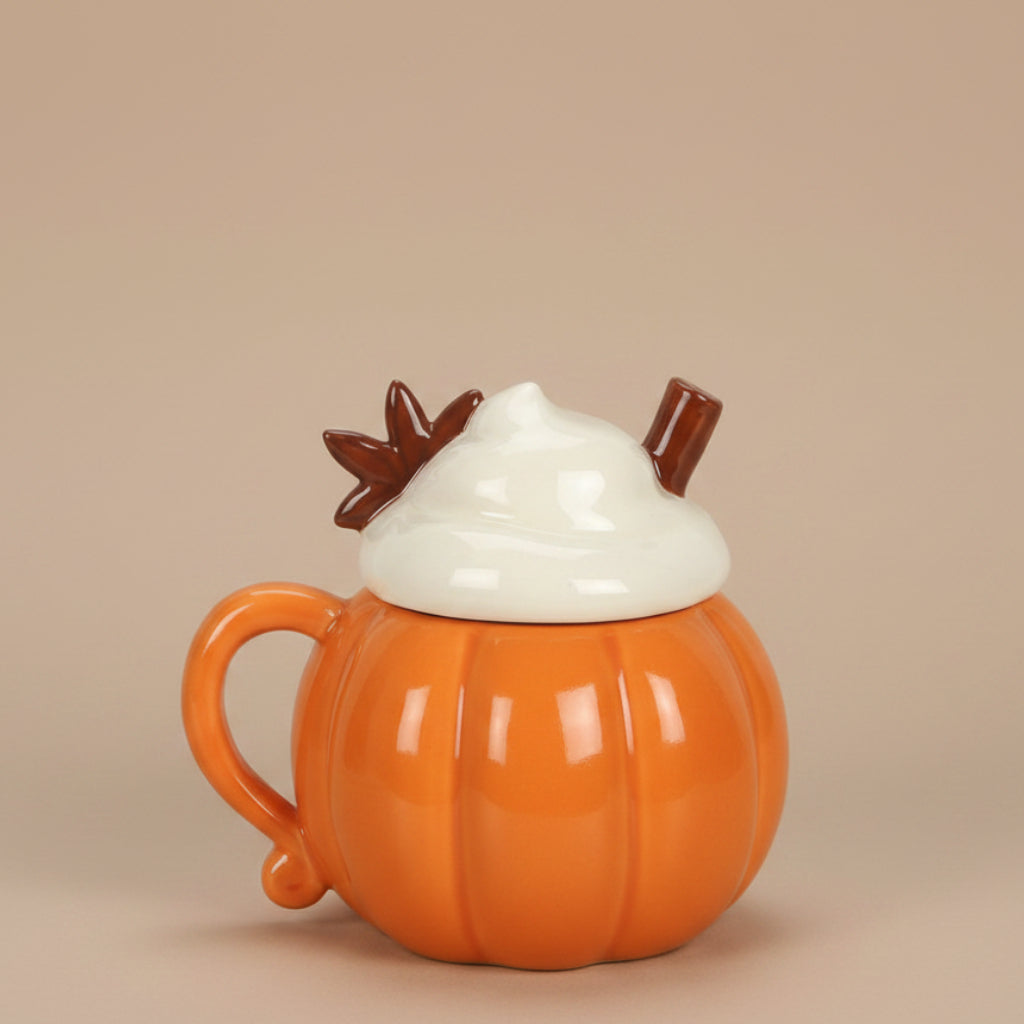 Pumpkin-shaped mug with a lid resembling whipped cream and chocolate leaves on a brown background