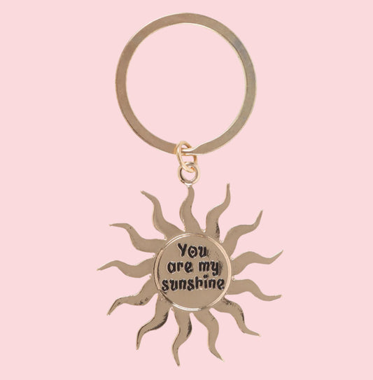 Sun-shaped keychain with 'You are my sunshine' text on a pink background
