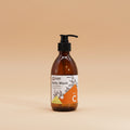Brown bottle of body wash with a pump and label on a orange background