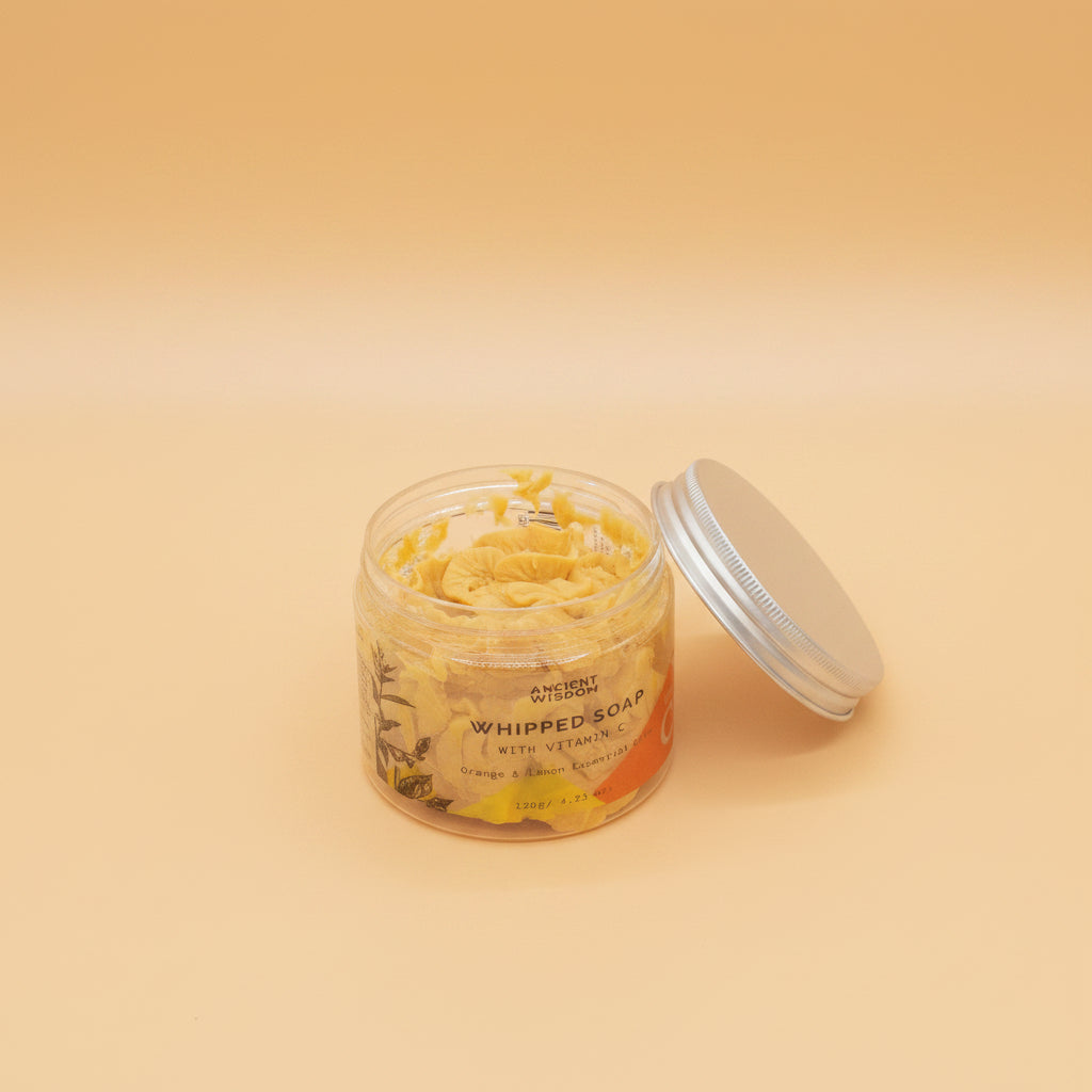 Jar of whipped soap with a silver lid on a light orange background