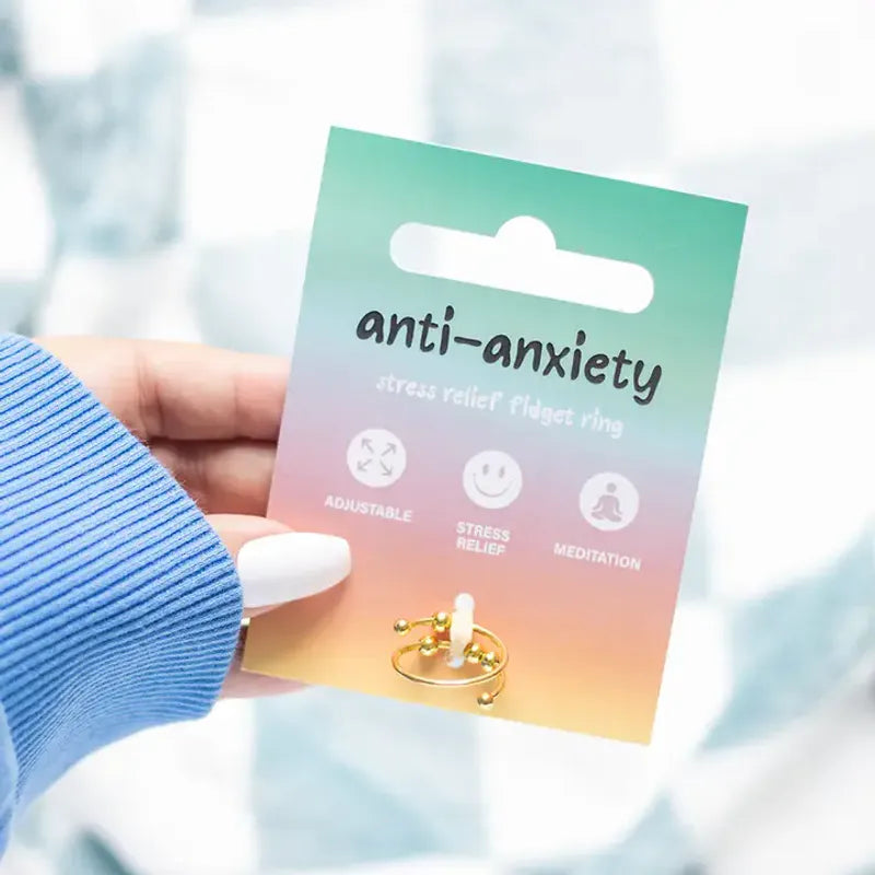 Hand holding a 'anti-anxiety' stress relief fidget ring packaging with a gradient design.