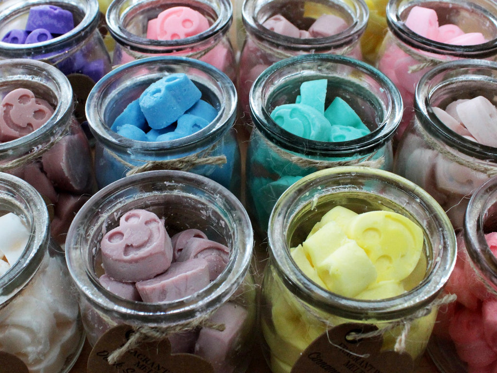 Jars filled with colorful wax melt hearts on a wooden surface