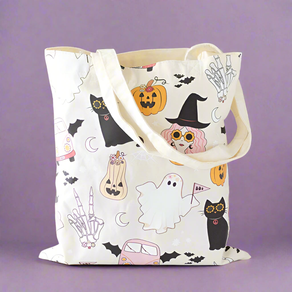 Tote bag with Halloween-themed design featuring cats, ghosts, and pumpkins on a neutral background.