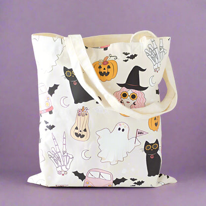 Tote bag with Halloween-themed design featuring cats, ghosts, and pumpkins on a neutral background.