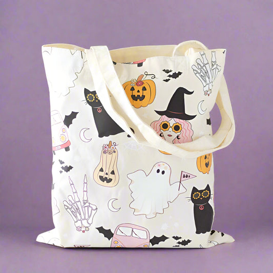 Tote bag with Halloween-themed design featuring cats, ghosts, and pumpkins on a neutral background.